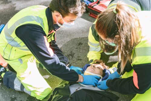 Paramedics using a collar to immobilize a woman experiencing catastrophic injuries in a car accident.