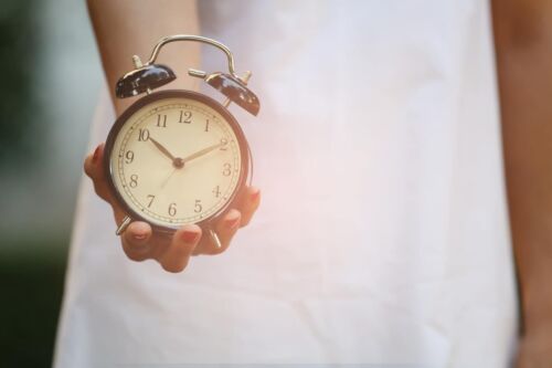 Woman holding out an alarm clock. Visual concept for a blog discussing statute limitations sexual assault.